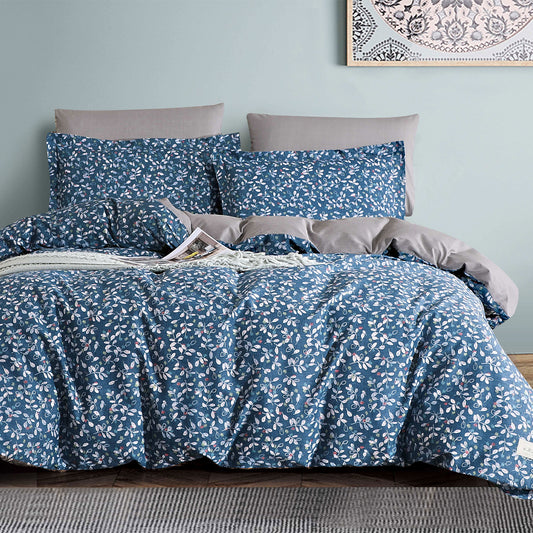 Blue floral bedding set on a bed with gray pillows against a light blue wall.