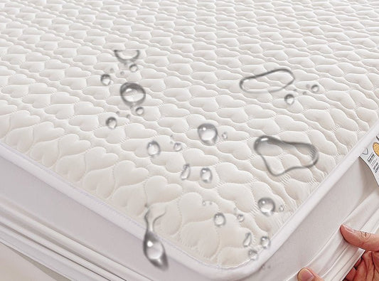 A close-up view of a waterproof quilted fit baby mattress protector with water droplets on its surface.