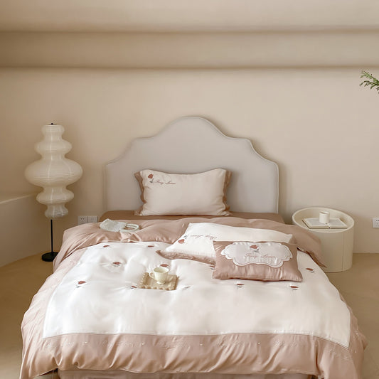 A beige Tencel rose embroidered duvet cover set on a bed, with a matching pillowcases and a floor lamp in the room.