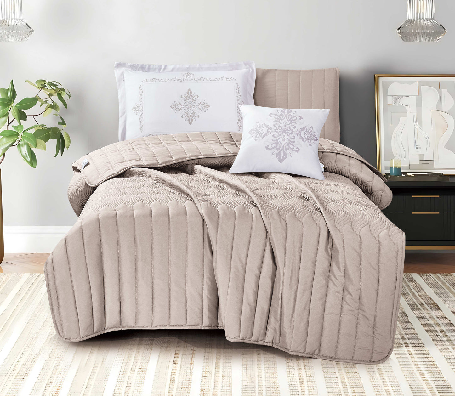 Beige quilted comforter set on a bed in a bedroom setting with pillows and a plant.