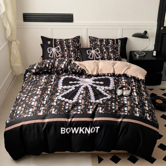 A bedding set with a black and white bow print, displayed on a bed with pillows and a comforter.