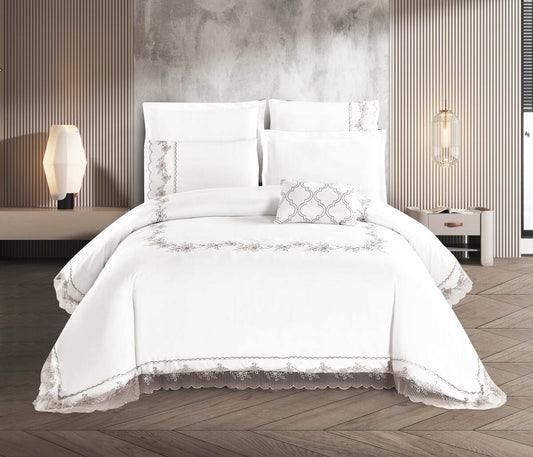 A white comforter set with lace detailing, displayed on a bed in a room with a modern aesthetic.