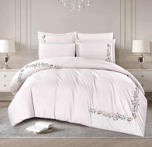 A white comforter set with floral embroidery, displayed in a bedroom setting with pillows and a duvet cover.