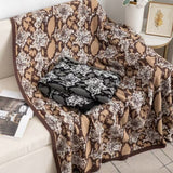 A brown, beige, and black hand-fringed throw with a geometric pattern draped over the back of a sofa.