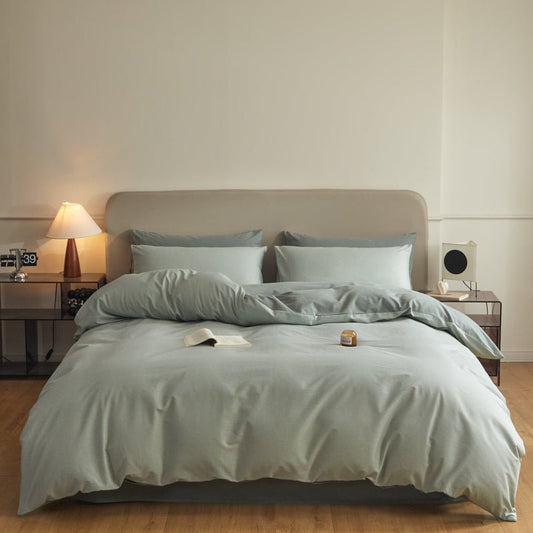 A duvet cover set with green stripes on a bed in a bedroom setting, with a nightstand and a lamp.