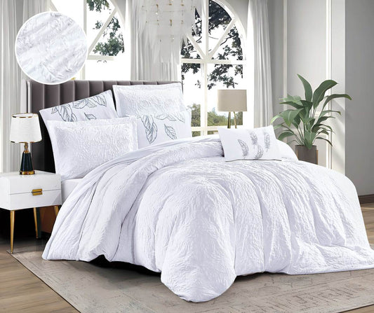 A white duvet cover with a floral print, displayed on a bed in a bedroom setting with a window, lamp, and plant in the background.