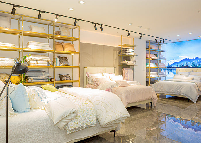 Bedroom with multiple beds and shelves displaying bedding and decor.