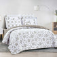 Bed with floral-patterned comforter and pillows in a bedroom setting.