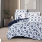 Navy and white floral patterned bedding set on a bed in a bedroom.