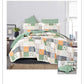 Patchwork quilt set on a bed with green pillows in a bedroom setting.
