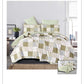 Patchwork quilt set on a bed with green pillows in a bedroom setting.