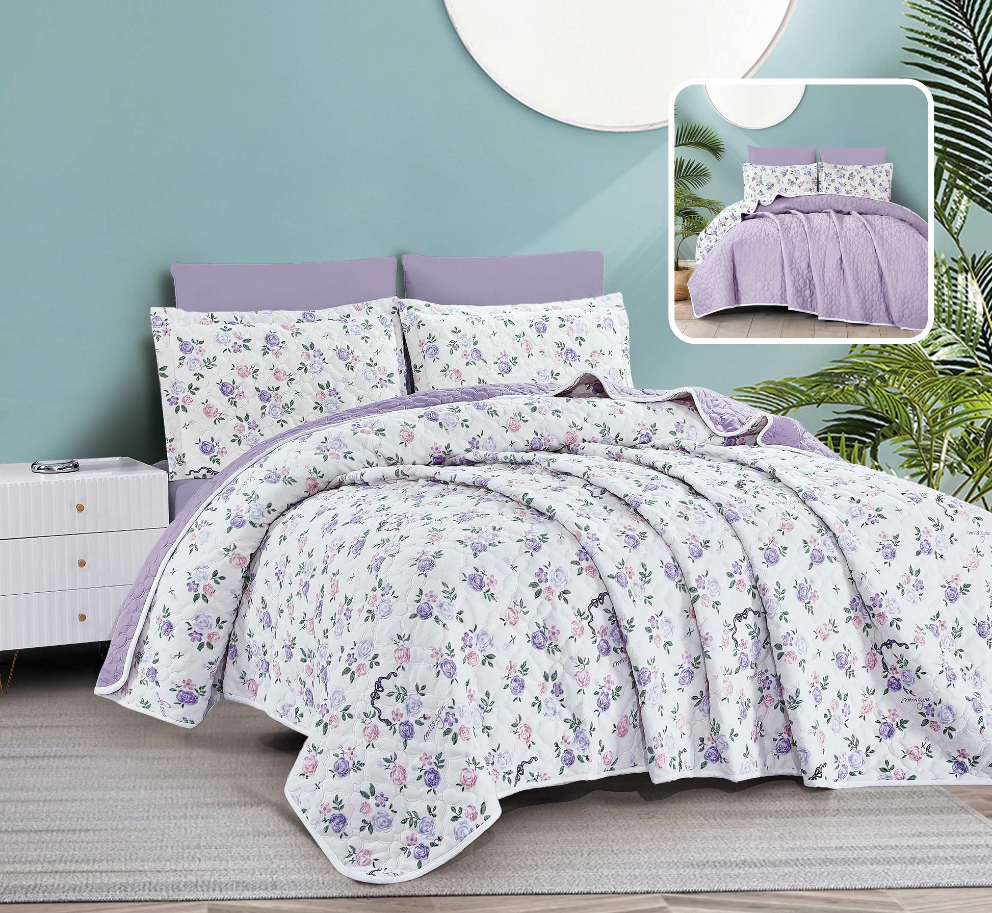 Floral bedding set with purple accents on a bed in a room with a light blue wall.