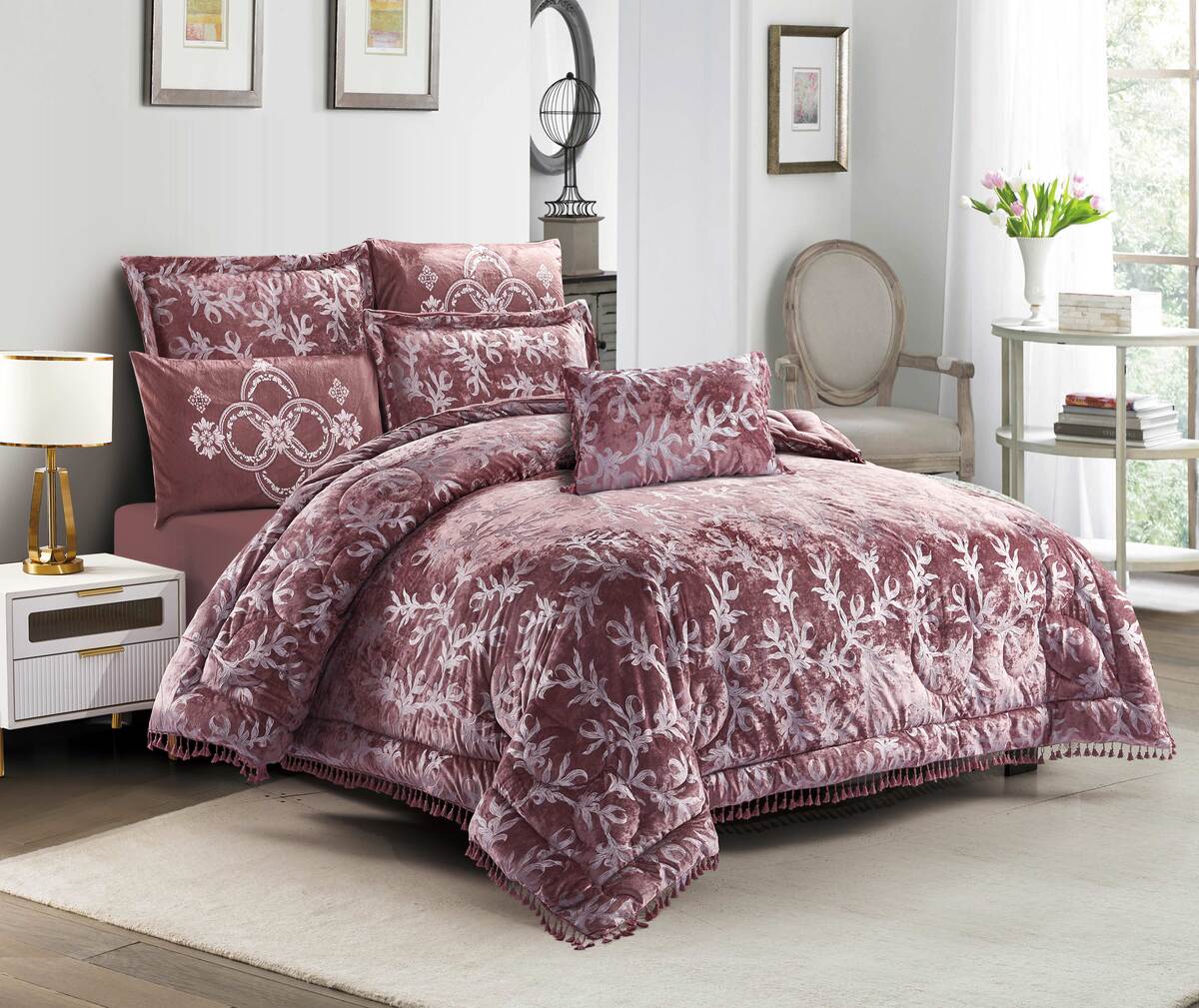 A burgundy lace quilted comforter set with pom-pom trim displayed in a bedroom setting, including a comforter, pillowcases, and a bedsheet.