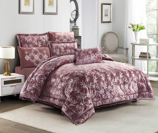A burgundy lace quilted comforter set with pom-pom trim displayed in a bedroom setting, including a comforter, pillowcases, and a bedsheet.