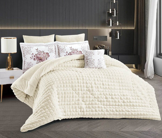 A beige quilted comforter set with a heart pattern, displayed on a bed with matching pillowcases and a lamp in the background.