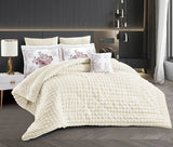 A beige quilted comforter set with a heart pattern, displayed on a bed with matching pillowcases and a lamp in the background.