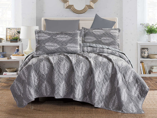 A gray coverlet with a botanical lace pattern displayed on a bed in a bedroom setting.
