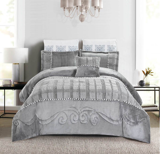 A gray velvet pom-pom quilted comforter set on a bed, with decorative pillows and a headboard in the background.
