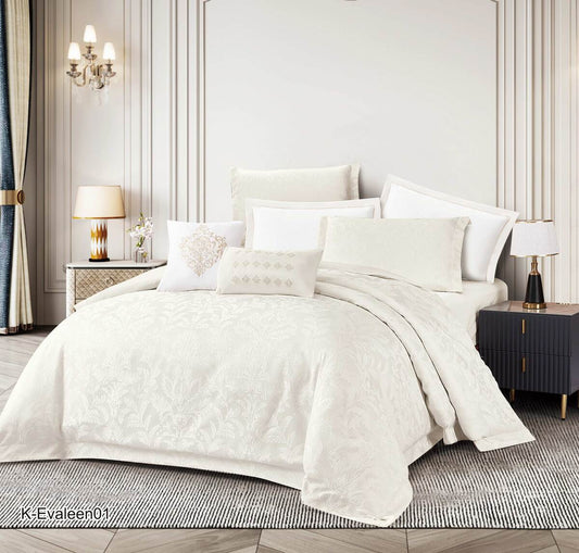 A cream-colored floral comforter set on a bed, with matching pillows and comforter spread across the bed in a room with elegant decor.