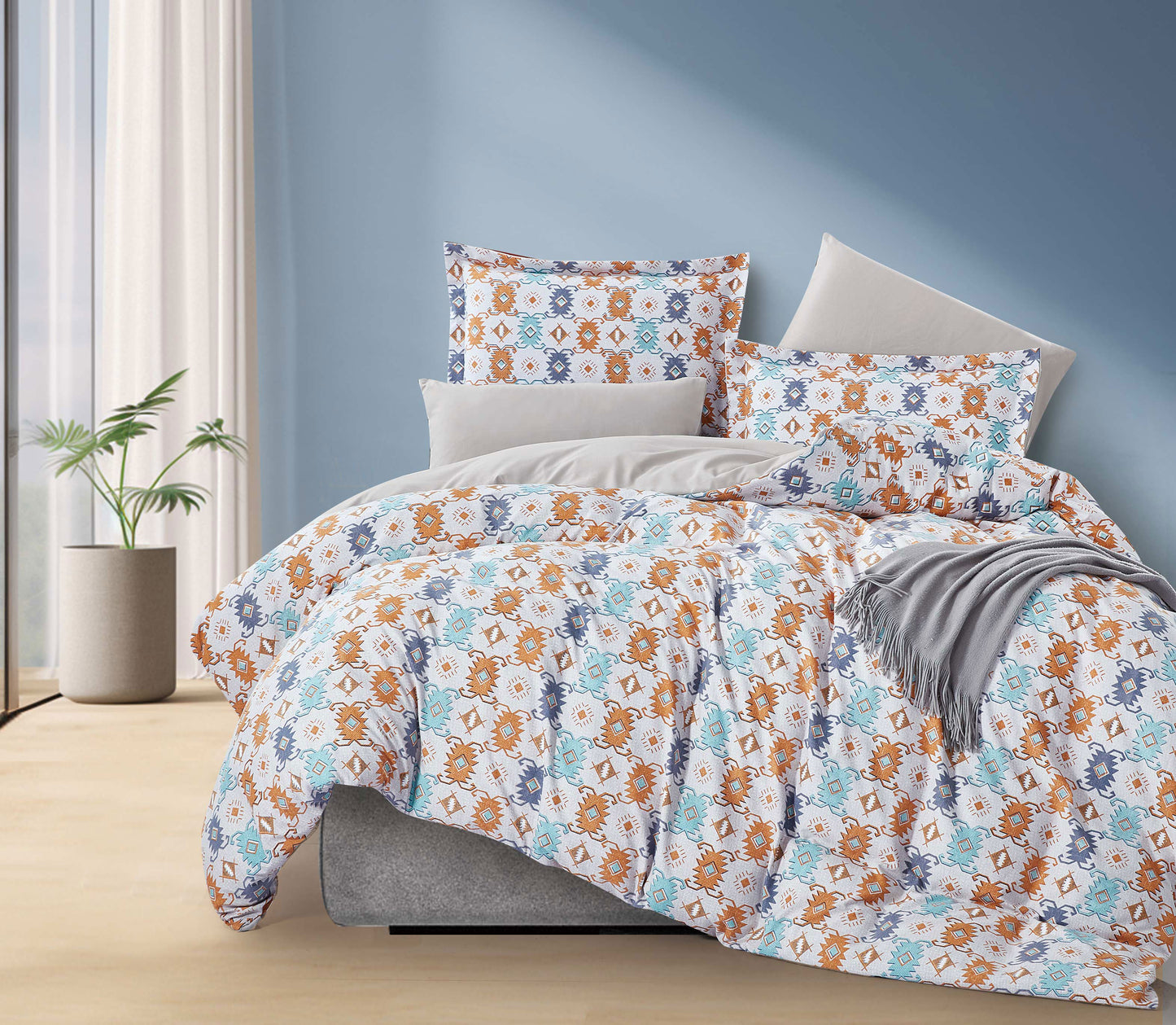 Floral patterned comforter set on a bed in a bedroom with a blue wall.