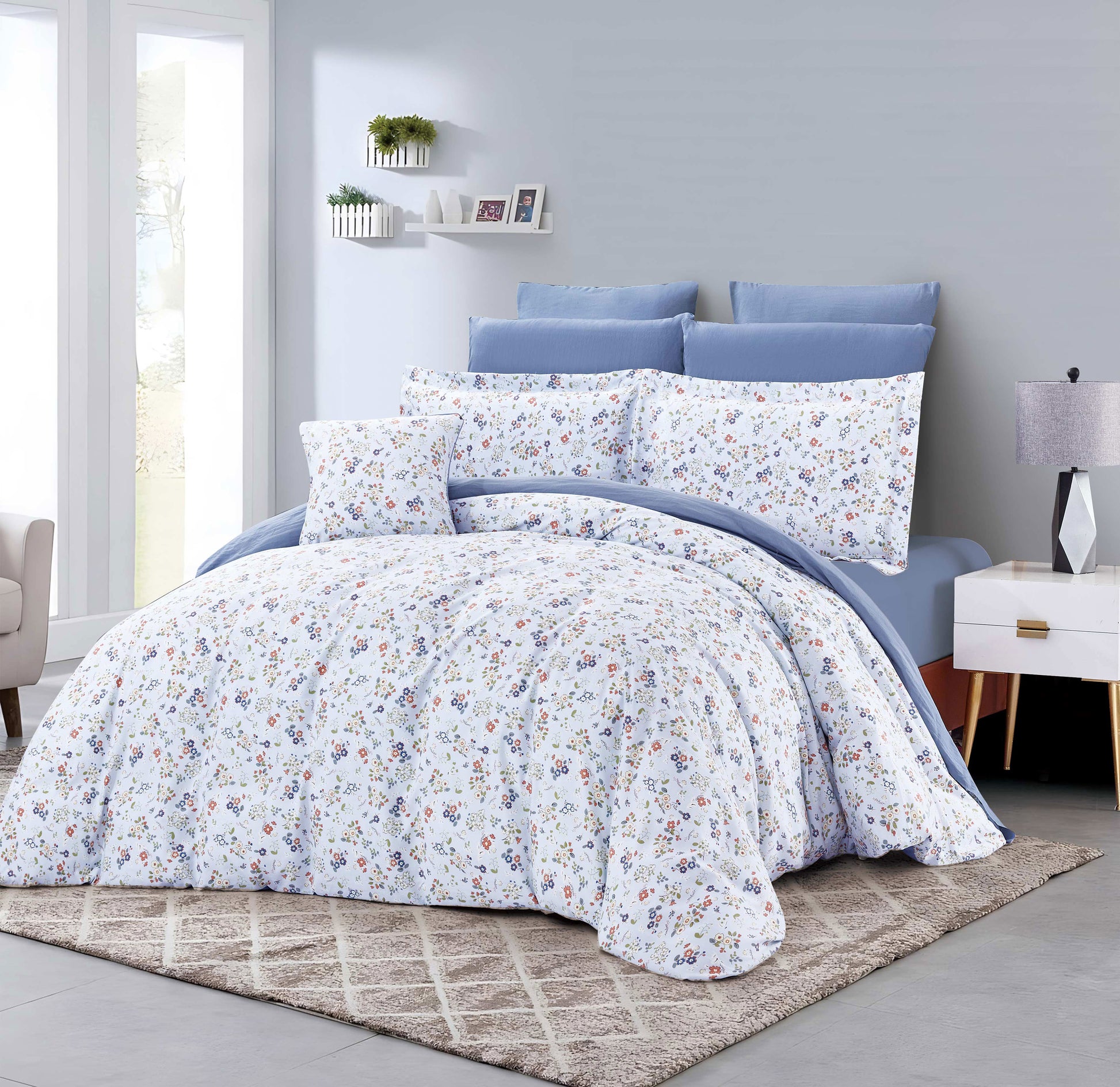 Floral bedding set on a bed in a bedroom with light blue walls and a nightstand.