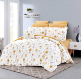 Floral comforter set on a bed in a bedroom with yellow pillows and a gray wall.