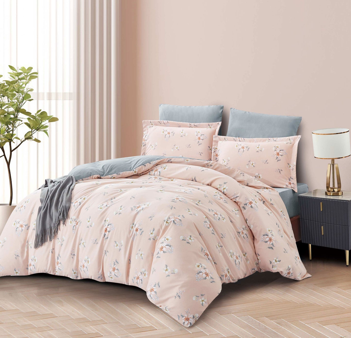 Floral bedding set on a bed in a bedroom with a lamp and plant.