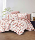 Polka dot bedding set on a bed with a lamp and plant in the background.