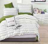 Bedroom with striped bedding and green pillows on a bed.