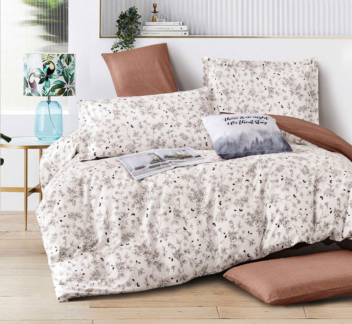 Floral patterned bedding set on a bed with pillows and a lamp in the background.