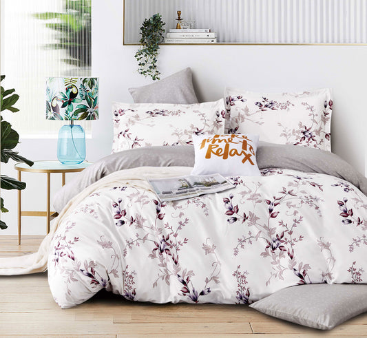 Floral bedding set on a bed in a well-decorated room with plants and books.