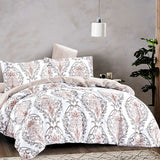 Floral patterned comforter set on a bed in a bedroom setting with a plant and lamp.