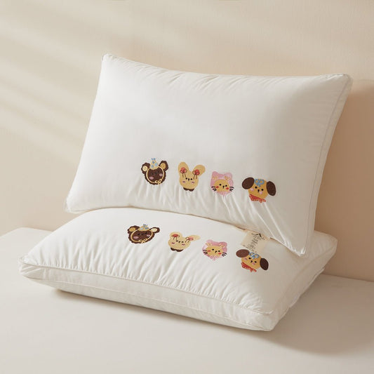 Two white pillows with cute animal embroidery designs on them, placed on a bed.