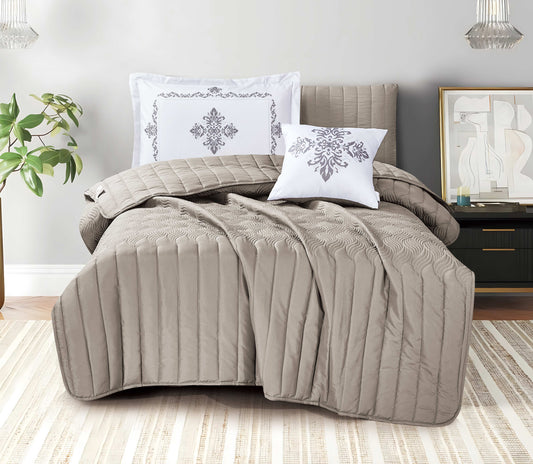 Quilted brown comforter set on a bed with decorative pillows in a bedroom setting.